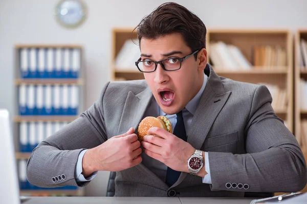 Un om de afaceri înfometat care mănâncă sandwich cu mâncare nesănătoasă — Fotografie, imagine de stoc