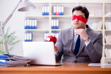 Ofiste masasında oturan gözü bağlı iş adamı.