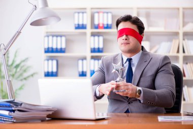 Ofiste masasında oturan gözü bağlı iş adamı.