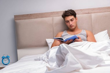 Adam yatakta kitap okumak