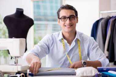 Genç terzi yeni elbiseler üzerinde çalışıyor.