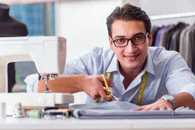 Genç terzi yeni elbiseler üzerinde çalışıyor.