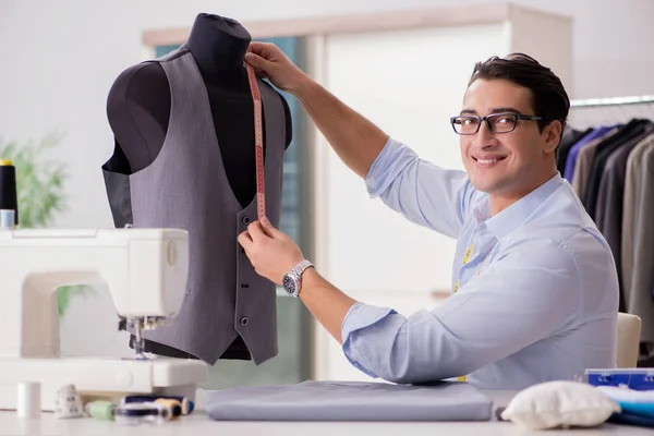 Jovem alfaiate trabalhando em roupas novas — Fotografia de Stock