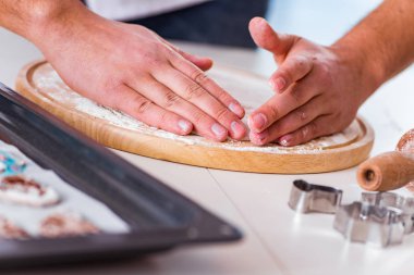 Genç adam mutfakta kurabiye pişiriyor.