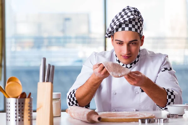 Young man cooking cookies in kitchen