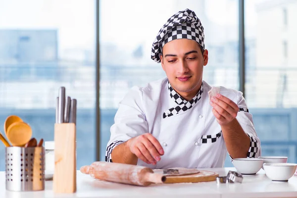 Young man cooking cookies in kitchen