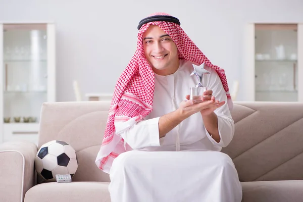 若いですarab男見サッカー座っています上のソファ — ストック写真