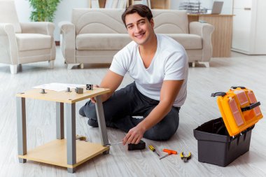 Adam evde mobilya montajı yapıyor.