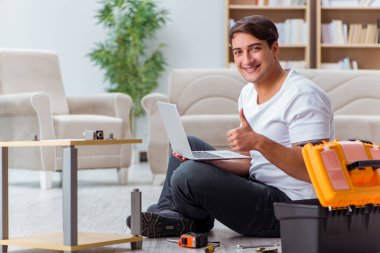 Adam evde mobilya montajı yapıyor.