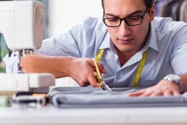 Genç terzi yeni elbiseler üzerinde çalışıyor.