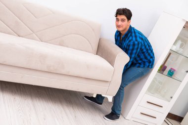 Genç adam kanepeyi taşıyor.