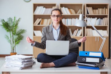 İş kadını ofiste meditasyon yapıyor.