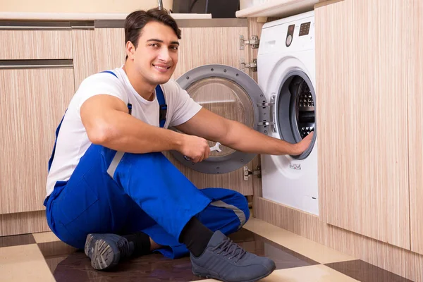 Reparador reparando lavadora en la cocina —  Fotos de Stock