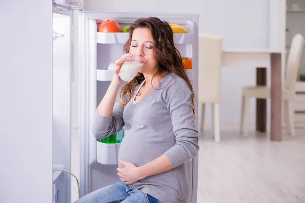 Mulher grávida perto de geladeira à procura de alimentos e lanches — Fotografia de Stock