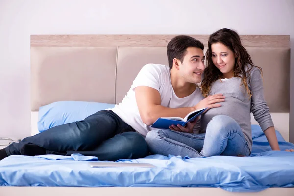 Familia joven con esposa embarazada esperando al bebé en la cama —  Fotos de Stock