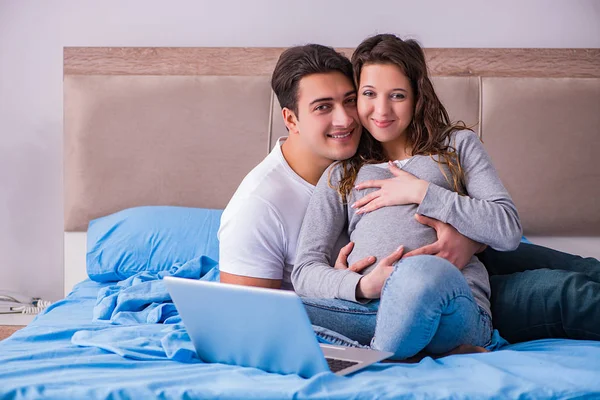 Familia joven con esposa embarazada esperando al bebé en la cama —  Fotos de Stock