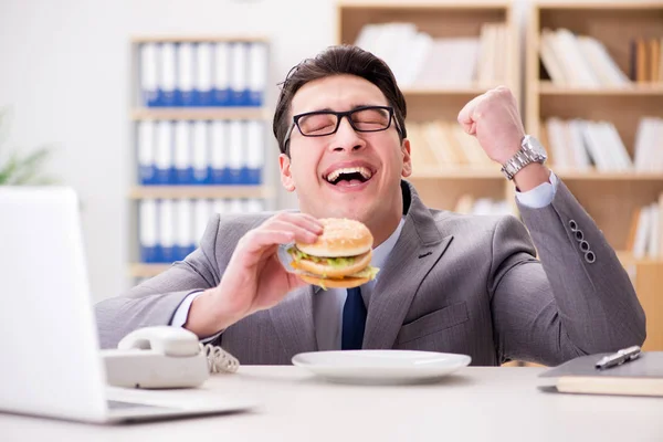 Голодний смішний бізнесмен їсть бутерброд з нездоровою їжею — стокове фото
