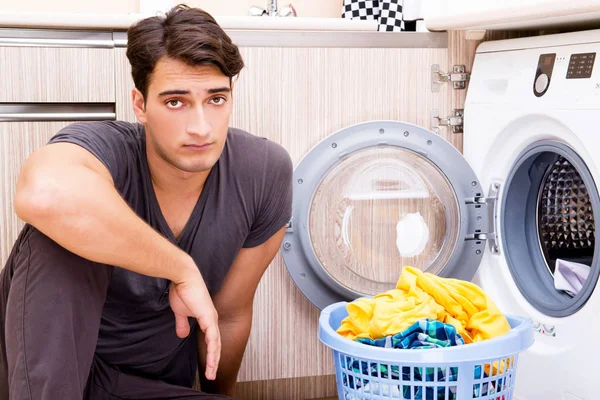 Genç koca evde çamaşır yıkıyor. — Stok fotoğraf