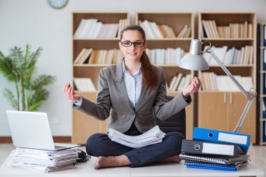 İş kadını ofiste meditasyon yapıyor.