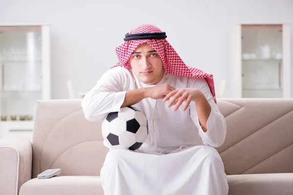 Young arab man watching football sitting on sofa — Stock Photo, Image