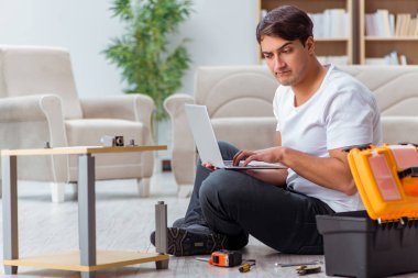 Adam evde mobilya montajı yapıyor.