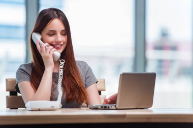 Genç bayan ofiste telefonla konuşuyor.