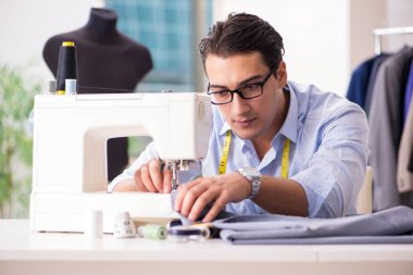 Genç terzi yeni elbiseler üzerinde çalışıyor.