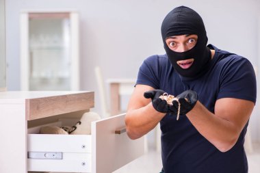 Soyguncu kar maskesi takıp değerli şeyler çalıyor.