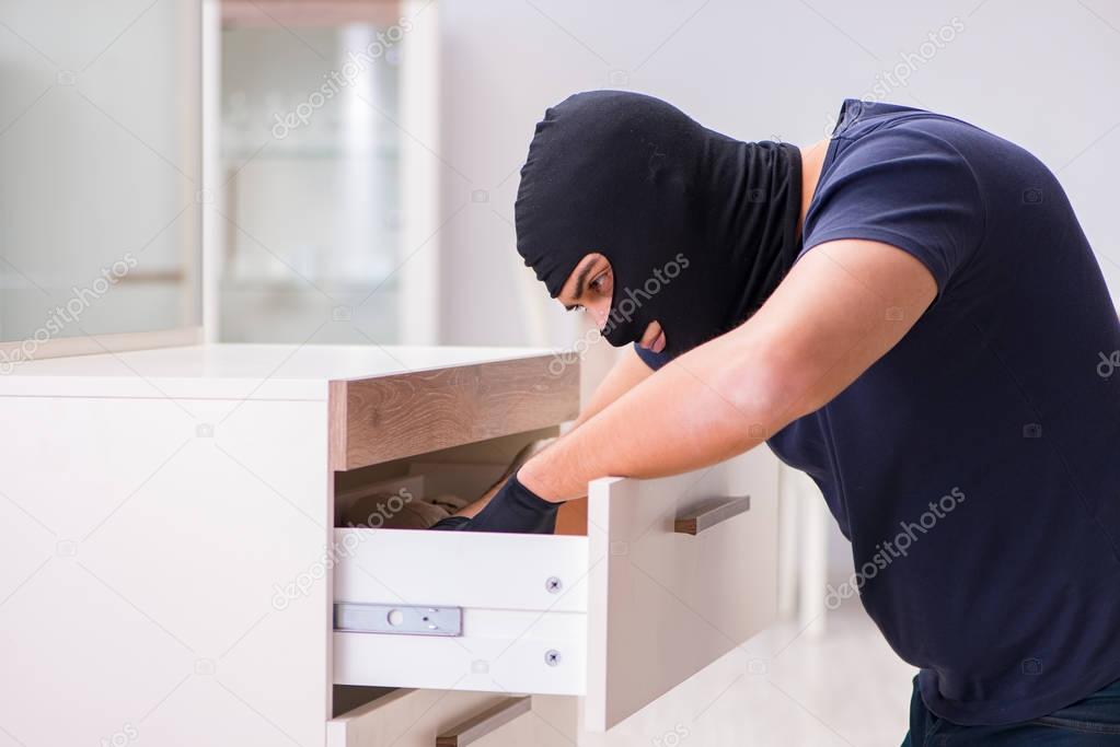 Robber wearing balaclava stealing valuable things