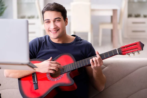 Ung man övar gitarr hemma — Stockfoto