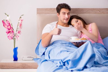 Mutlu bir aile yatakta kahvaltı yapıyor.