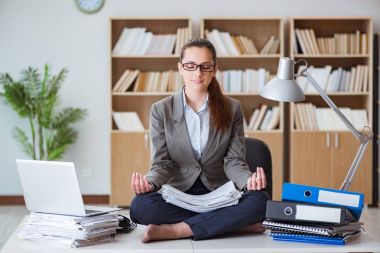 İş kadını ofiste meditasyon yapıyor.