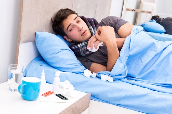 Chory człowiek z grypą leżący w łóżku — Zdjęcie stockowe