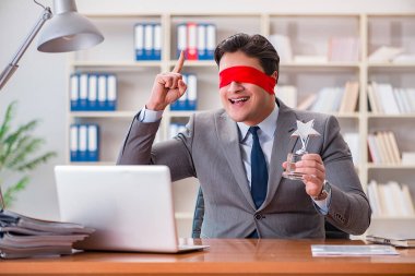 Ofiste masasında oturan gözü bağlı iş adamı.