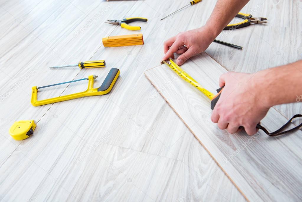 Repairman laying laminate flooring at home