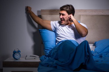 Genç adam yatakta gürültüden boğuşuyor.