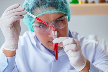 Laboratuvar hastanesinde kan testi üzerinde çalışan genç bir doktor.