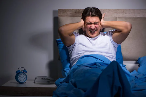 Молодой человек борется с шумом в постели — стоковое фото
