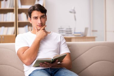 Kanepede kitap okuyan bir adam.