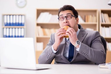 Aç komik iş adamı abur cubur sandviç yiyor.