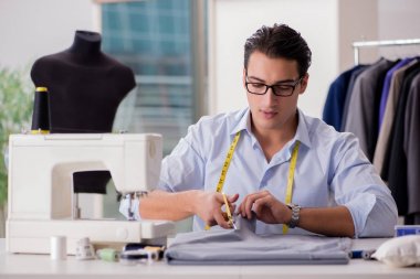 Genç terzi yeni elbiseler üzerinde çalışıyor.