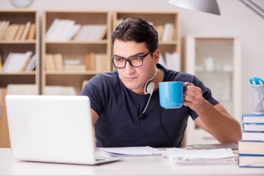 Genç öğrenci fincandan kahve içiyor.