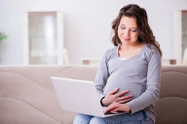 Schwangere arbeitet am Laptop und sitzt auf Sofa — Stockfoto