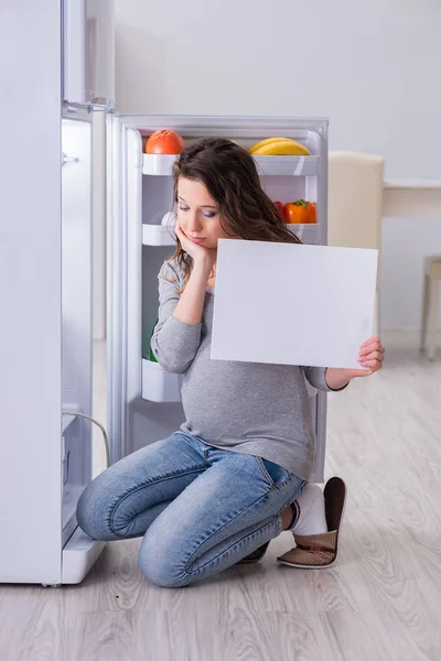 Έγκυος γυναίκα κοντά στο ψυγείο με κενό μήνυμα — Φωτογραφία Αρχείου