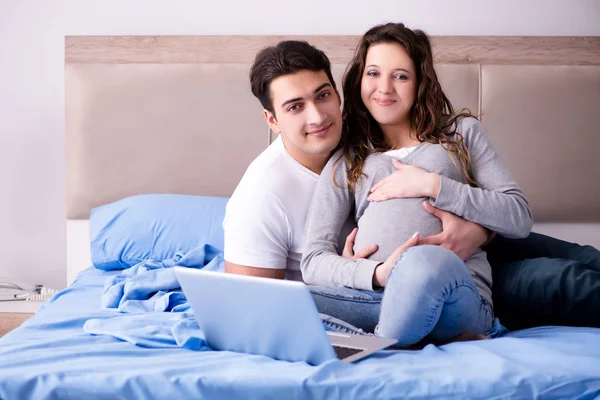 Молода сім'я з вагітною дружиною очікує дитину в ліжку — стокове фото