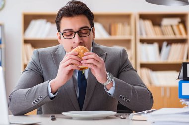 Aç komik iş adamı abur cubur sandviç yiyor.