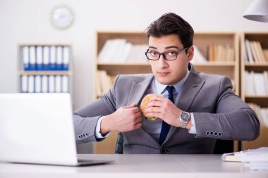 Aç komik iş adamı abur cubur sandviç yiyor.