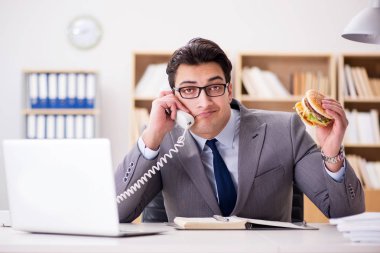 Aç komik iş adamı abur cubur sandviç yiyor.