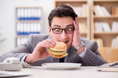 Aç komik iş adamı abur cubur sandviç yiyor.