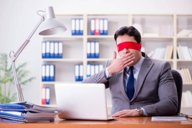 Ofiste masasında oturan gözü bağlı iş adamı.